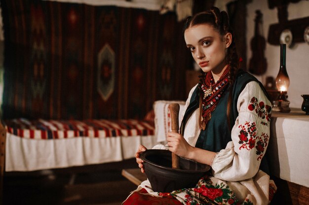 Charming Ukrainian girl in a traditional dress cooking in traditional kitchen