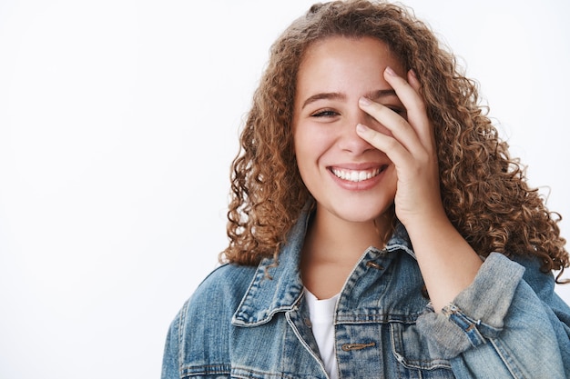 Free photo charming upbeat optimstic dreamy curly-haired plump girl smiling white teeth blushing flirty hide half face palm have fun laughing cute, studio wall