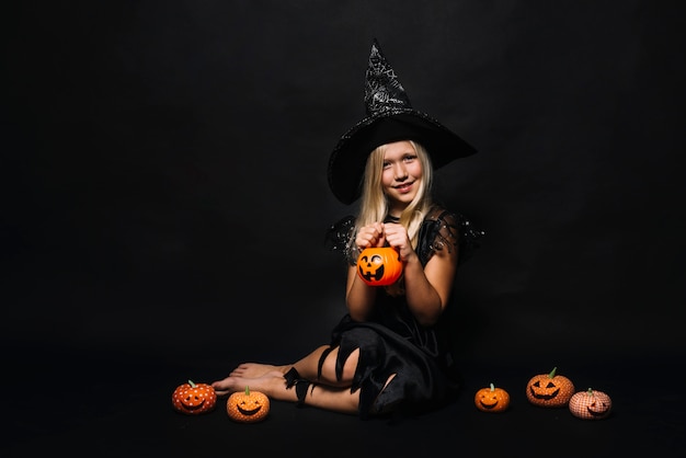 Free photo charming witch with small jack-o-lanterns