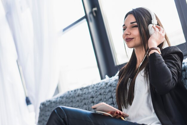 Charming woman enjoying music on sofa