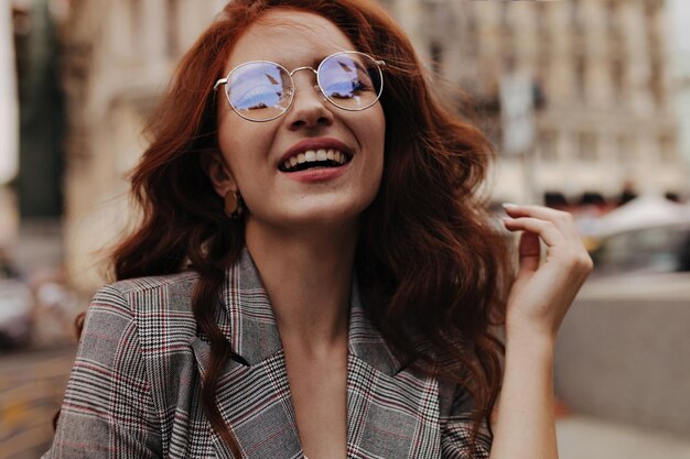 Charming woman in eyeglasses laughing outside
