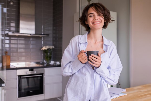 Charming woman at home smiling and holding cup