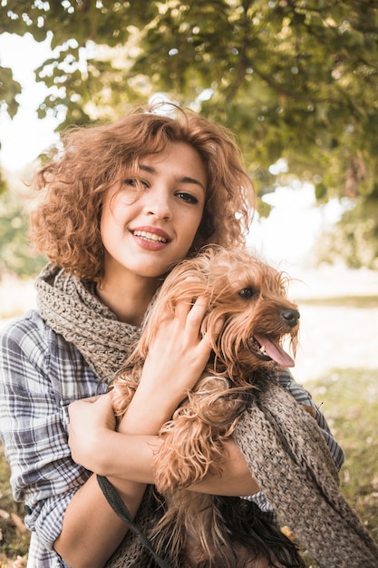 Free photo charming woman petting dog in park