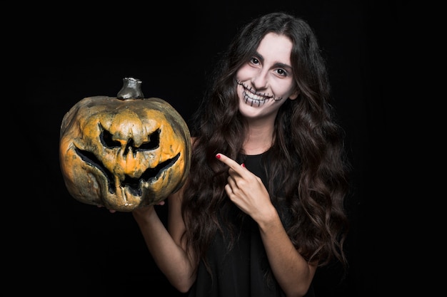 Free photo charming woman pointing halloween pumpkin