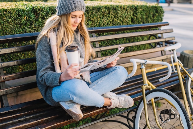 Donna affascinante leggendo il giornale sulla panchina