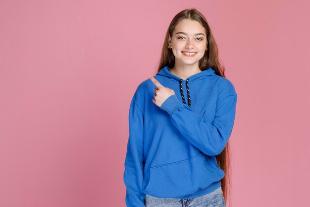 Charming woman showing direction with left hand gesturing while sincerely smiling at camera