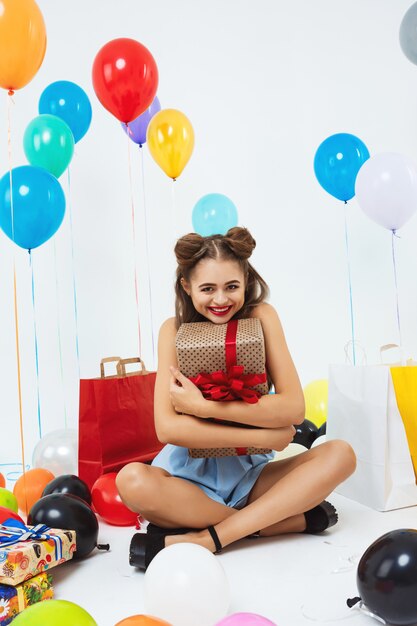 Charming woman sits in lotus position holding big gift box