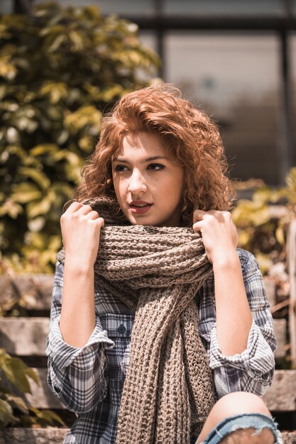 Charming woman sitting on steps and holding scarf 