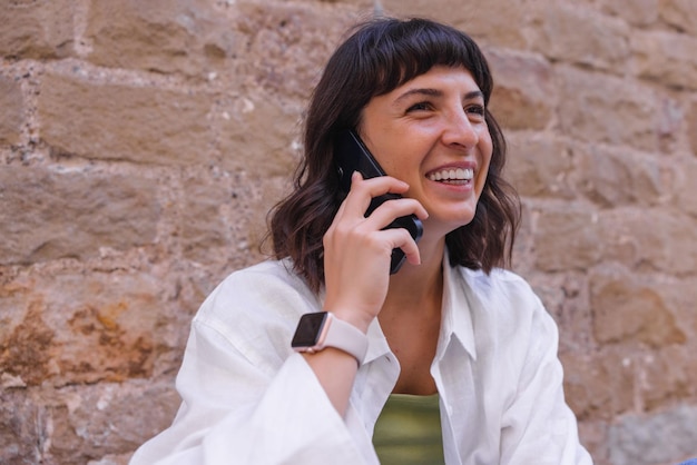 La donna affascinante sorride parlando sul cellulare