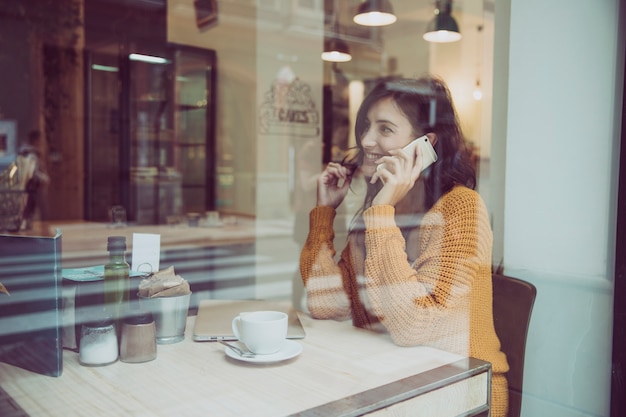 Charming woman speaking on phone in cafe