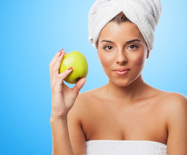 Charming woman in towel holding green apple