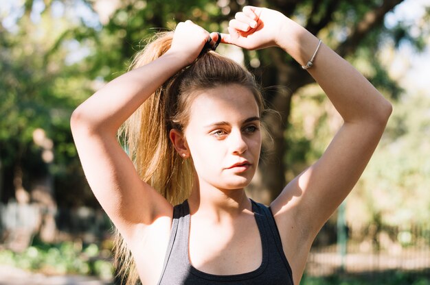 Charming woman tying ponytail