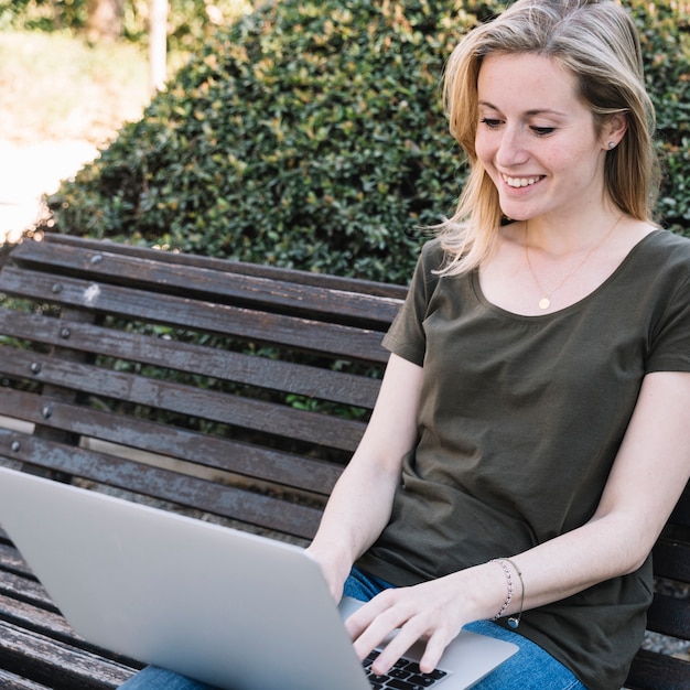 Charming woman using laptop in park