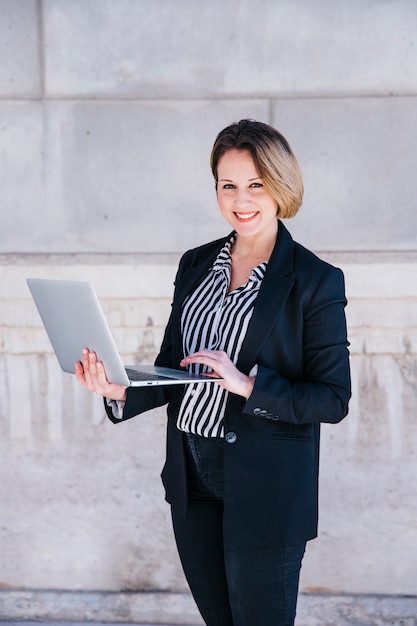 Charming woman using laptop on street