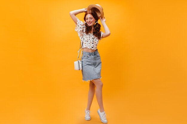 Charming woman wears straw hat. Woman in stylish skirt and shirt is smiling on isolated background.