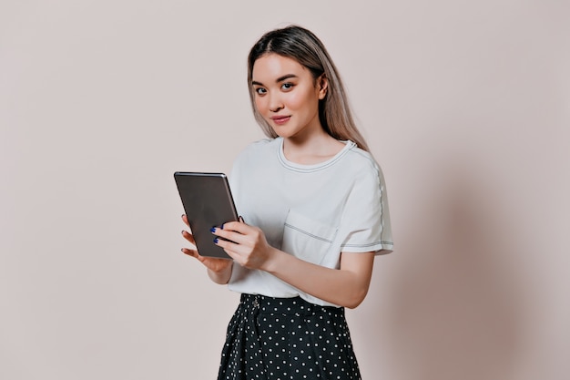 Charming woman in white t-shirt holding computer tablet