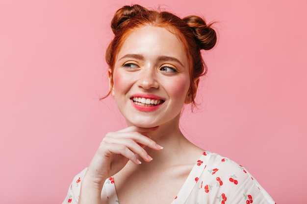 Free photo charming woman in white tshirt with cherries smiles looks into camera and bites her lip coquettishly