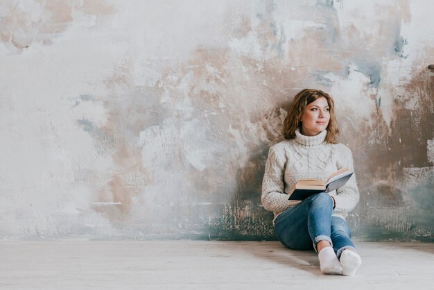 Charming woman with book near wall
