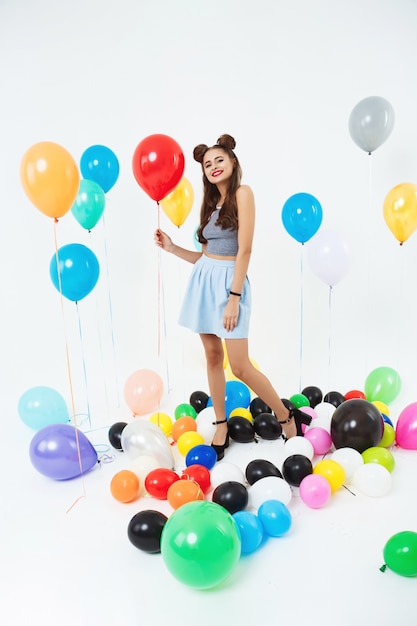 Charming woman with cool hairstyle holding red helium balloon