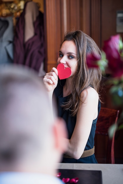 Charming woman with ornament heart and man at table 