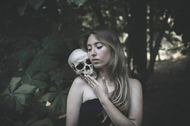 Charming woman with skull in thicket