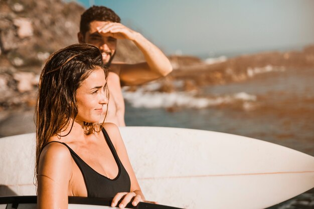 Charming woman with surfboard near boyfriend