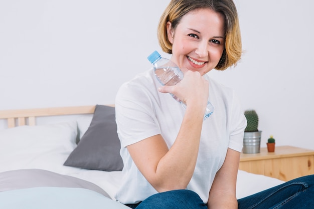 Charming woman with water bottle in bedroom