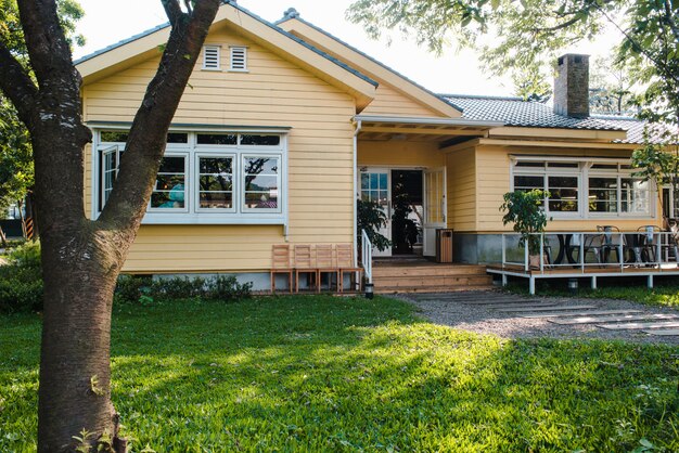 나무 창문과 푸른 잔디 정원이있는 매력적인 노란 집
