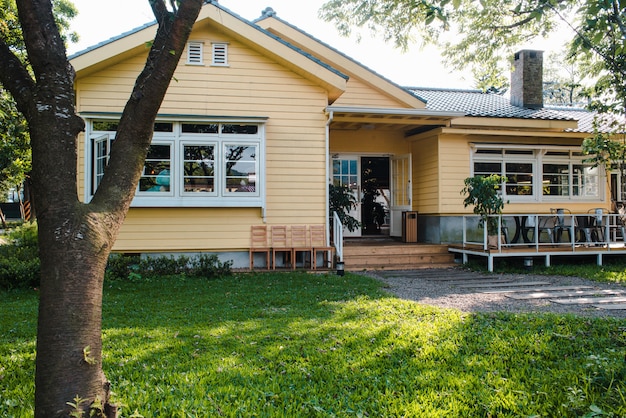 Charming yellow house with wooden windows and green grassy garden