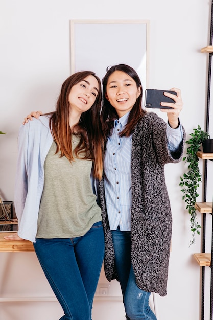 Charming young girlfriends taking selfie