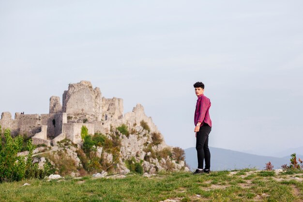 Charming young man standing near rock formation