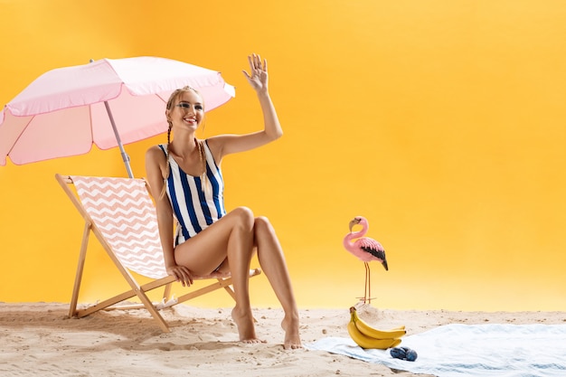 Free photo charming young model in striped swimsuit smiles and looks away