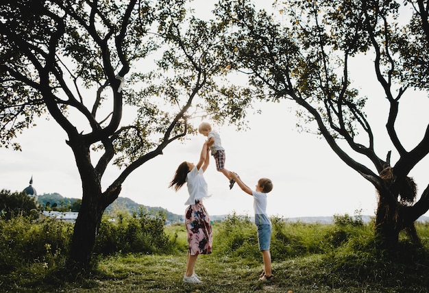 Free photo charming young mother hugs tender her little sons standing under