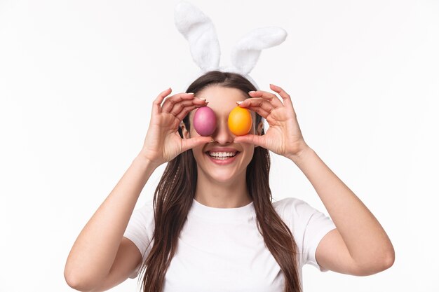 着色された卵を保持しているウサギの耳の魅力的な若い女性