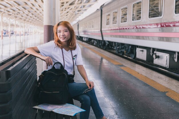 魅力的な若い女性がバックパックで駅に