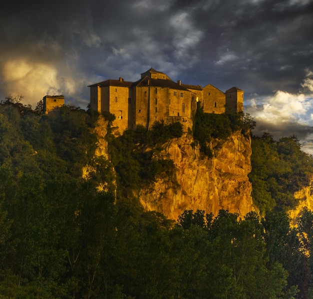 Chateau de bruniquel circondato dal verde e dalle rocce sotto un cielo nuvoloso durante il tramonto in francia