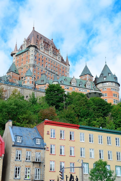 Замок Фронтенак днем с красочными зданиями на улице в Квебеке