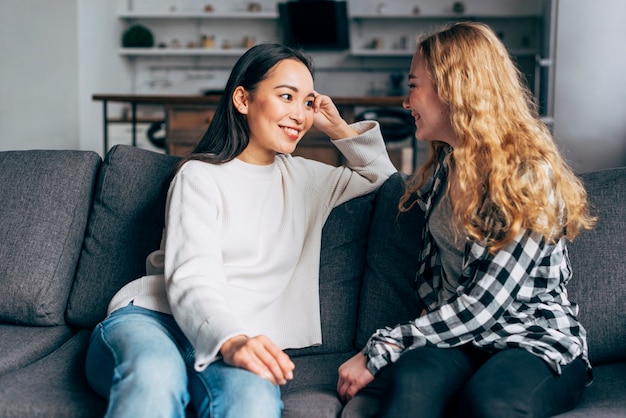 Chatting joyful best friends on couch