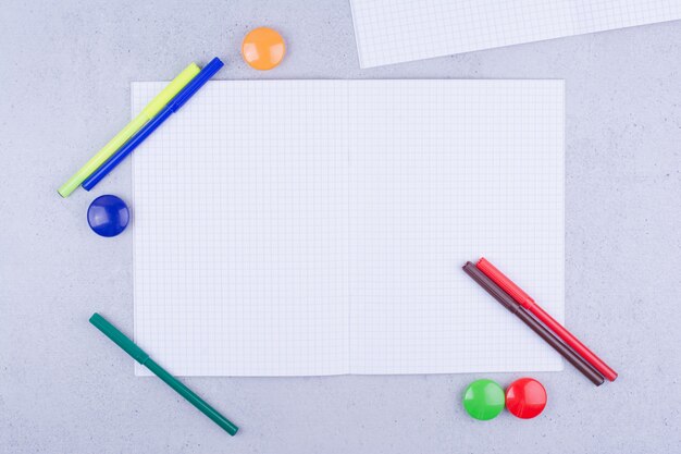 A checked blank paper with pens and pins around