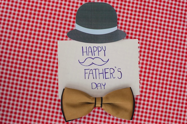 Бесплатное фото Клетчатая поверхность с галстуком-бабочкой и шляпой для отца