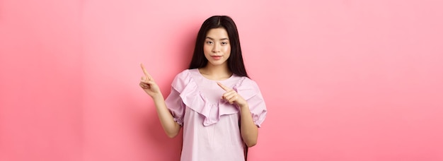 Нахальная азиатка показывает интересную рекламу, указывая пальцем прямо на логотип и улыбаясь куни