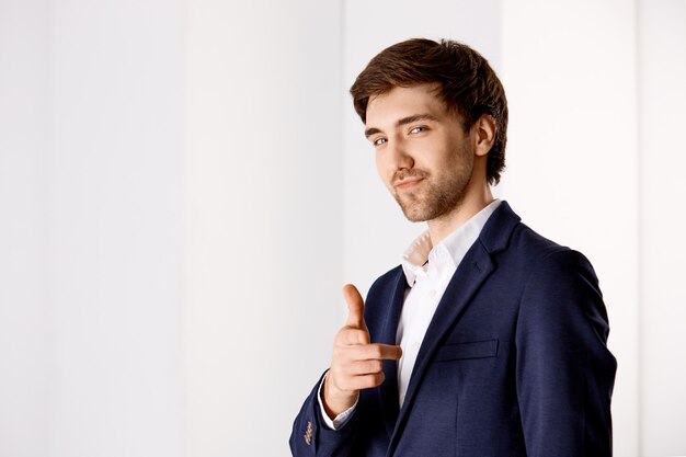 Cheeky confident handsome young businessman, pointing finger and smiling, praising you making good work