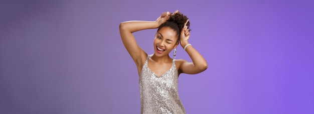 Free photo cheeky joyful playful africanamerican woman in silver stylish dress having fun party make horns inde