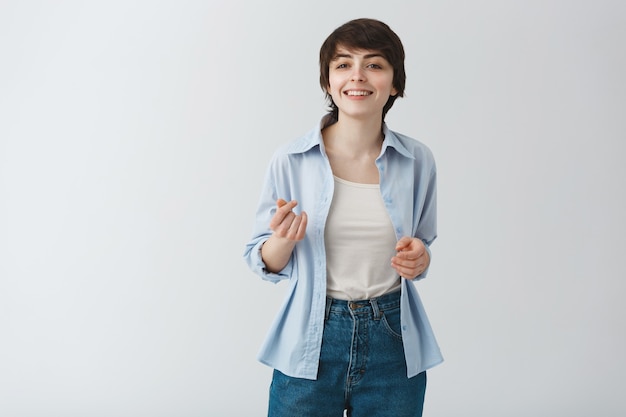 Cheeky smiling woman with short hair pointing, having conversation