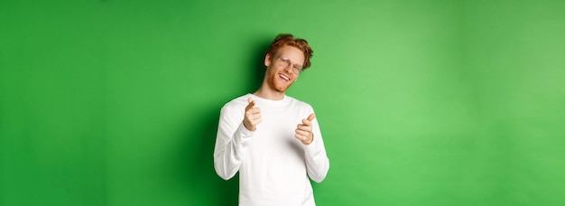 Free photo cheeky young man in glasses praising and congratulating you pointing fingers at camera and smiling s