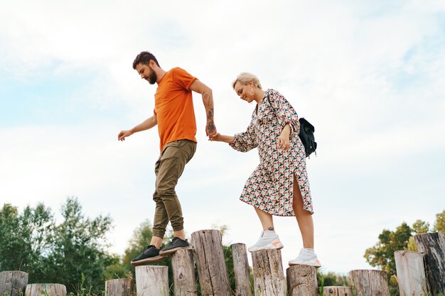 Cheerful active coupe walking on stumps on blue sky