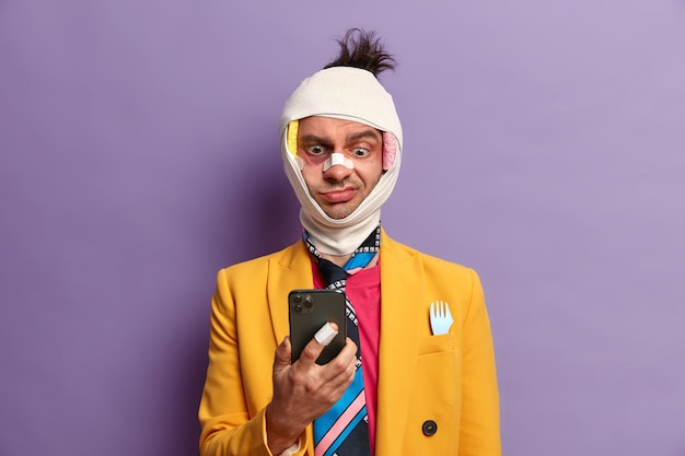 Free photo cheerful adult man has trauma of head, broken nose and bruises under eyes