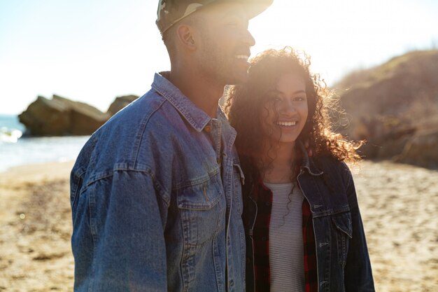 Cheerful african loving couple walking outdoors at beach