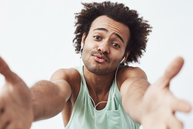 Cheerful african man in headphones rejoicing stretching hands