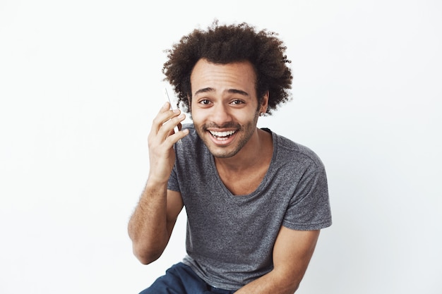 전화 말하기 웃는 쾌활한 아프리카 남자.